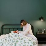 A mother cares for her child with a fever in a warm, cozy bedroom setting.