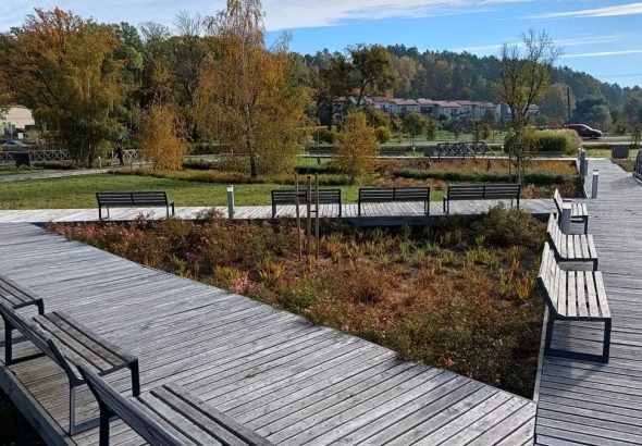 A tranquil autumn park in Bartążek, Poland, with wooden walkways and benches.
