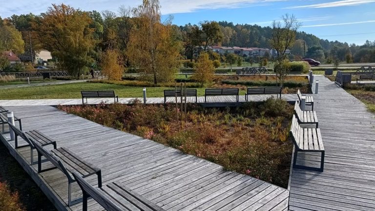A tranquil autumn park in Bartążek, Poland, with wooden walkways and benches.